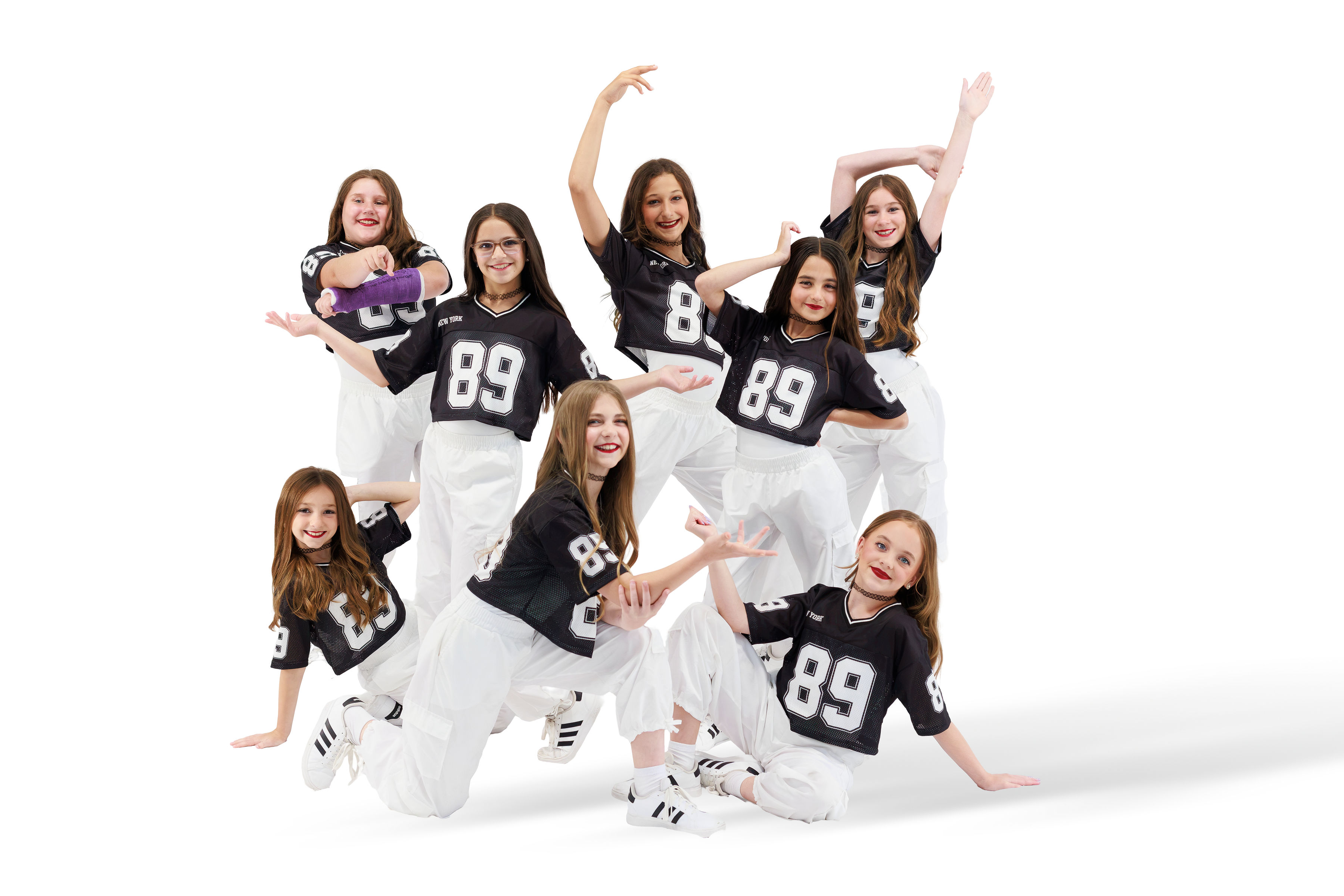 Under The Spotlight Dance Company dancers posing together in black jerseys and white pants